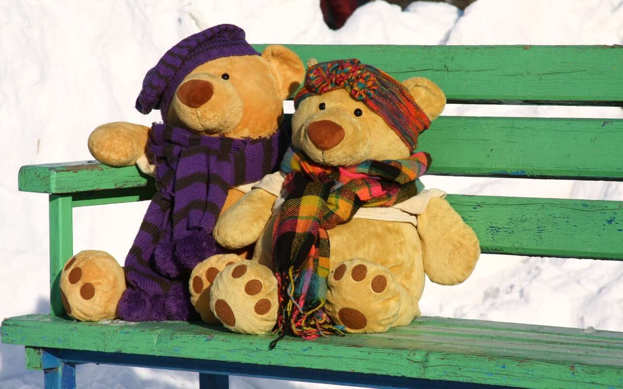 A male and female toy bear sitting on a bench